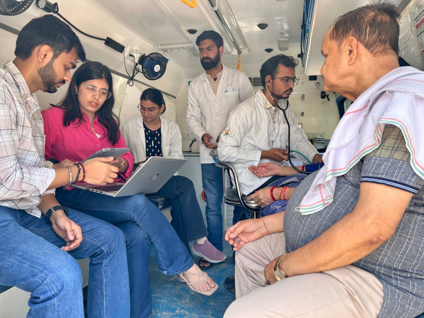 A mobile health team logging data on a laptop mid-visit
